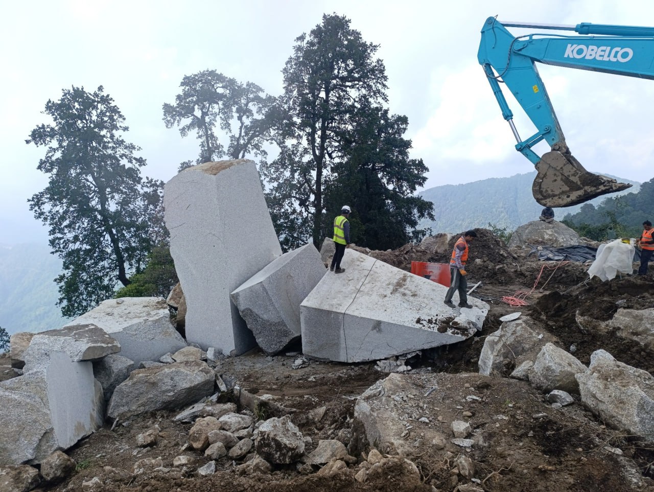 Large granite blocks, quarry workers and excavator at Kailash Granite Quarry in Palung.