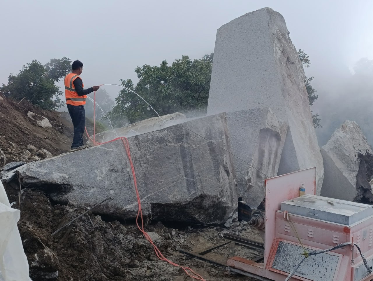 Quarry worker applying water during granite block cutting operations at Kailash Granite Quarry.